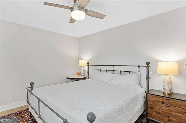 bedroom featuring baseboards, wood finished floors, and a ceiling fan