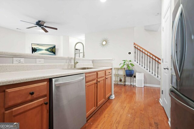 kitchen featuring light countertops, light wood-style flooring, ceiling fan, stainless steel appliances, and a sink
