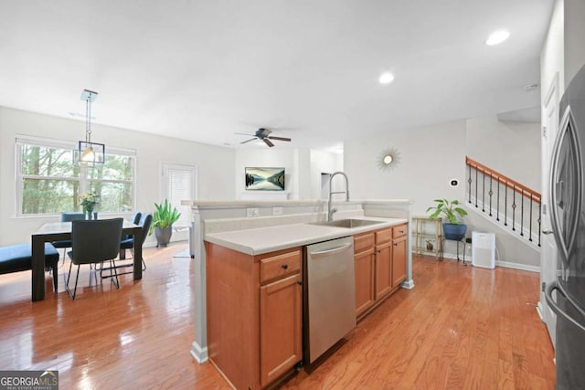 kitchen featuring a ceiling fan, a sink, stainless steel appliances, and light wood-type flooring