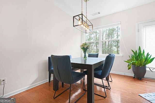 dining space featuring baseboards, visible vents, light wood-type flooring, and an inviting chandelier