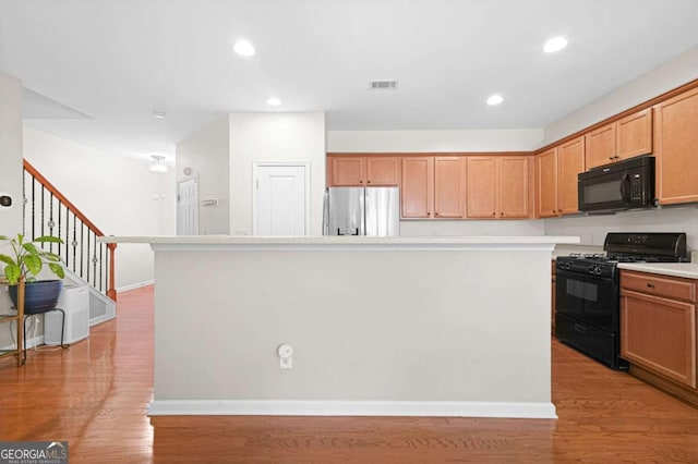 kitchen with light wood finished floors, visible vents, black appliances, and light countertops