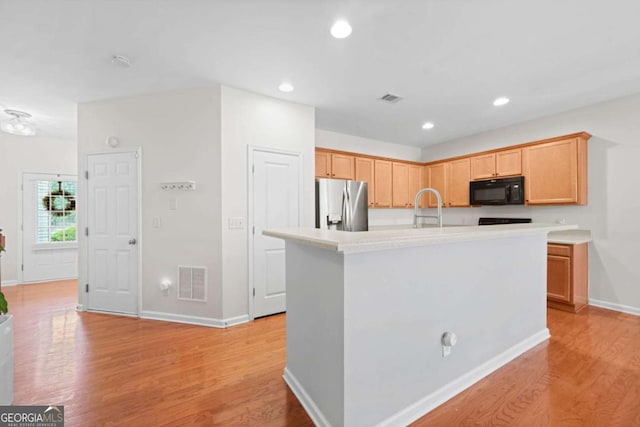 kitchen featuring light wood-type flooring, stainless steel fridge with ice dispenser, black microwave, and visible vents