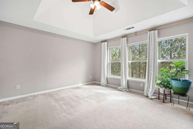 spare room with visible vents, a raised ceiling, carpet flooring, and a ceiling fan