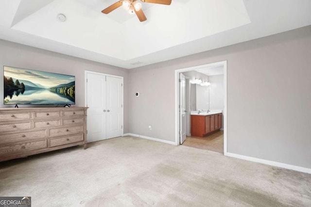 unfurnished bedroom with baseboards, light carpet, and a raised ceiling