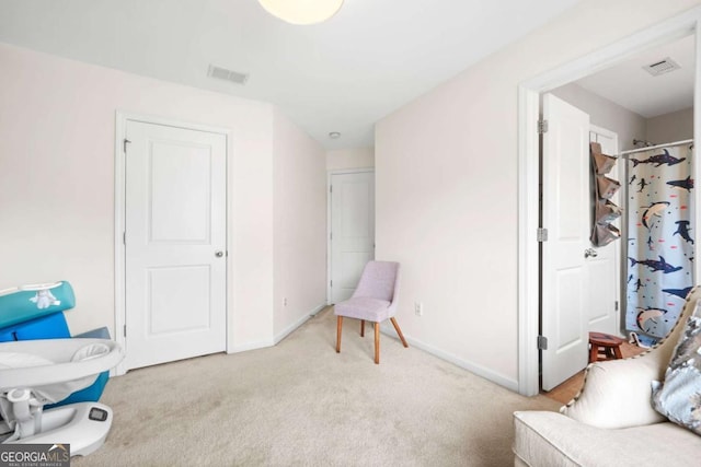 living area with baseboards, light colored carpet, and visible vents