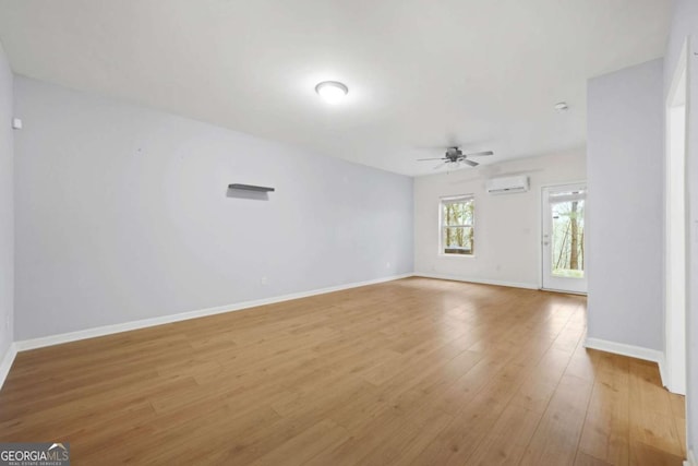 interior space with baseboards, a wall mounted AC, light wood-type flooring, and a ceiling fan