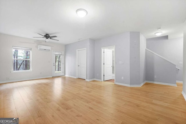 unfurnished living room with light wood-style floors, ceiling fan, baseboards, and an AC wall unit
