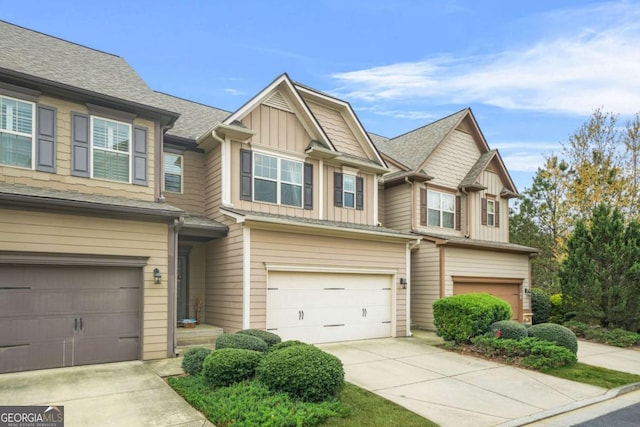 multi unit property with driveway, a garage, board and batten siding, and roof with shingles
