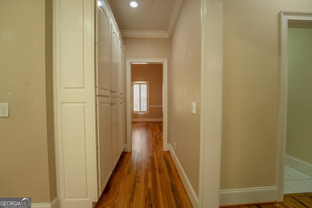 corridor featuring baseboards, crown molding, wood finished floors, and recessed lighting