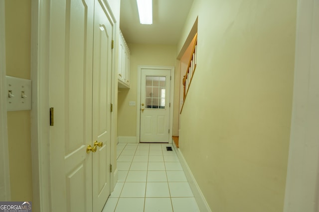 hallway with baseboards, light tile patterned flooring, and visible vents