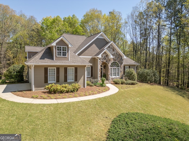 craftsman-style home with stone siding, a front lawn, and roof with shingles