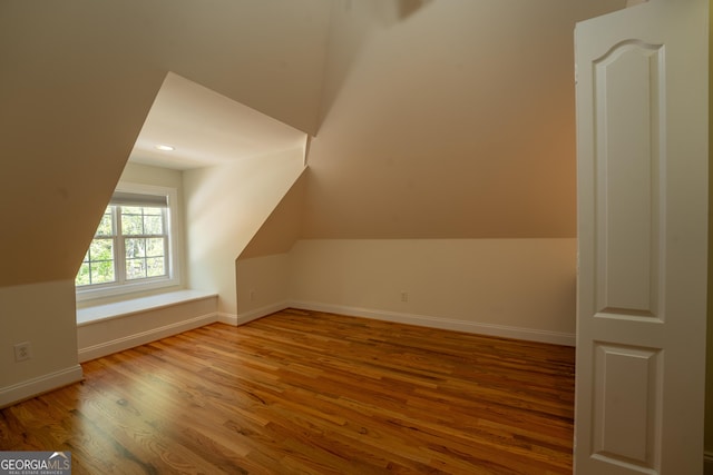 additional living space with vaulted ceiling, wood finished floors, and baseboards