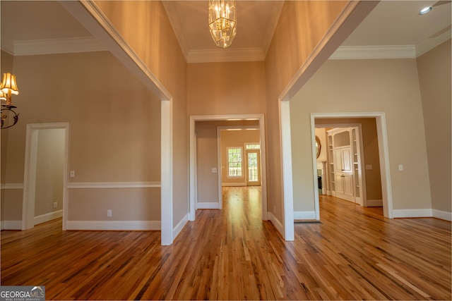 entryway with ornamental molding, wood finished floors, and a chandelier