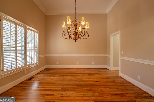 unfurnished dining area with ornamental molding, baseboards, a notable chandelier, and wood finished floors