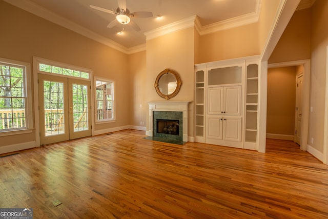 unfurnished living room featuring a premium fireplace, wood finished floors, a ceiling fan, and baseboards