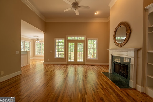 unfurnished living room with a ceiling fan, wood finished floors, a fireplace, and ornamental molding