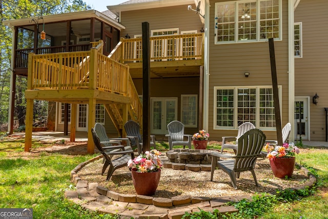 back of house with a deck, a sunroom, a patio area, an outdoor fire pit, and french doors