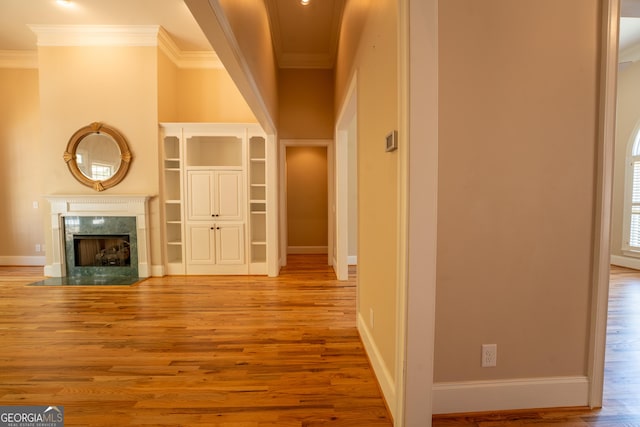 hallway with wood finished floors, baseboards, and ornamental molding