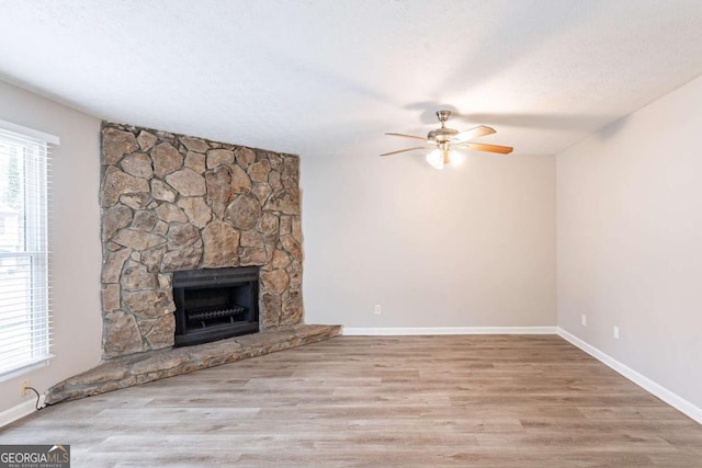 unfurnished living room with a healthy amount of sunlight, wood finished floors, a fireplace, and a ceiling fan