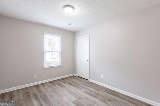unfurnished room with visible vents, baseboards, wood finished floors, and a textured ceiling