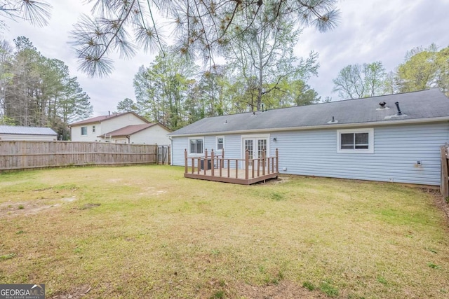rear view of house featuring french doors, fence, a deck, and a lawn