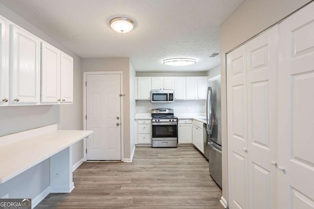 kitchen featuring light wood-style floors, appliances with stainless steel finishes, light countertops, and white cabinets