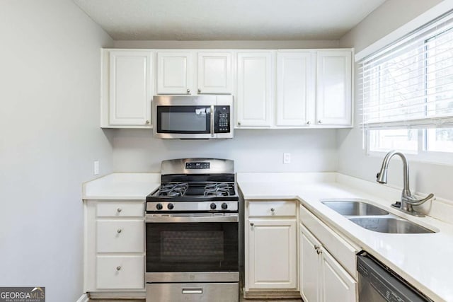 kitchen featuring white cabinets, light countertops, a sink, and appliances with stainless steel finishes