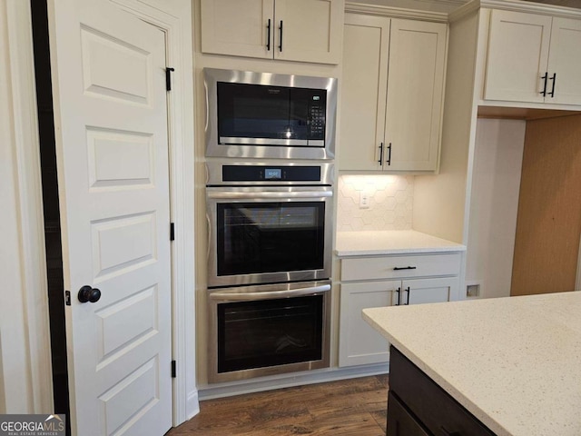 kitchen with dark wood finished floors, light stone countertops, backsplash, and appliances with stainless steel finishes