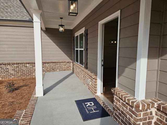 entrance to property with brick siding, a porch, and roof with shingles