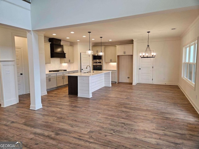 kitchen featuring premium range hood, appliances with stainless steel finishes, dark wood-type flooring, a sink, and an inviting chandelier