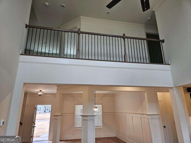 interior details featuring ceiling fan, a decorative wall, crown molding, and wainscoting