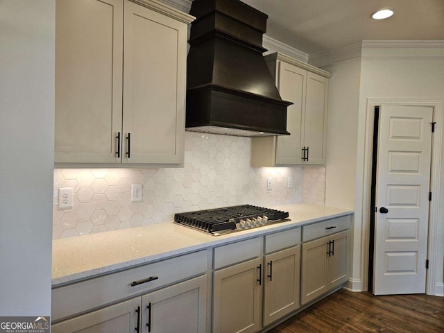 kitchen featuring backsplash, stainless steel gas stovetop, custom exhaust hood, ornamental molding, and dark wood-style flooring