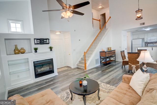 102 Manley Ct, Woodstock, GA 30188 - living area featuring a high ceiling, stairs, built in shelves, light wood-style flooring, and baseboards