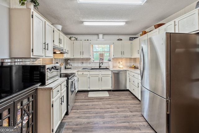 95 Joshua Ct, Zebulon, GA 30295 - kitchen with stainless steel appliances, under cabinet range hood, a textured ceiling, wood finished floors, and tasteful backsplash