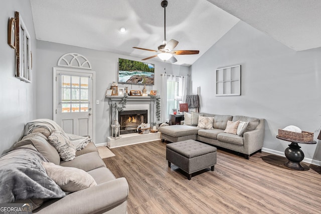 95 Joshua Ct, Zebulon, GA 30295 - living room featuring a ceiling fan, wood finished floors, a textured ceiling, a tiled fireplace, and vaulted ceiling