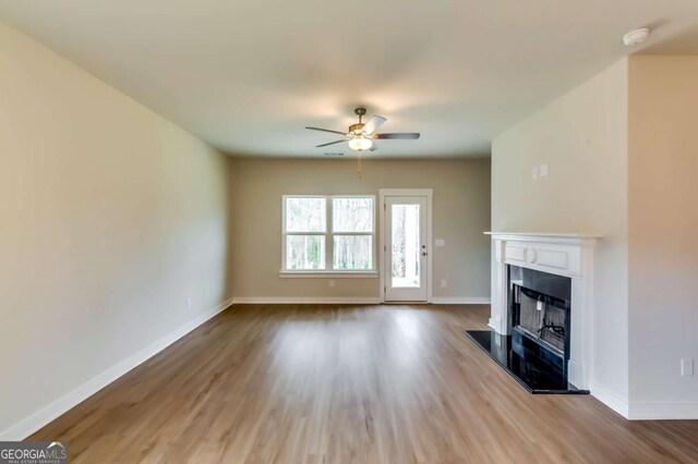 497 Principal Meridian Dr, Dallas, GA 30132 - unfurnished living room with ceiling fan, wood finished floors, a fireplace with raised hearth, and baseboards