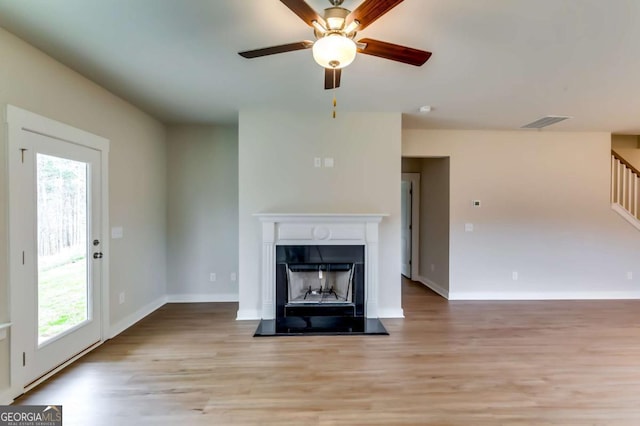 497 Principal Meridian Dr, Dallas, GA 30132 - unfurnished living room featuring light wood finished floors, ceiling fan, stairs, and a fireplace