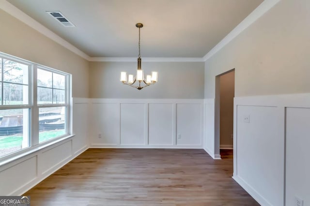 497 Principal Meridian Dr, Dallas, GA 30132 - unfurnished dining area featuring a decorative wall, a chandelier, crown molding, light wood-style flooring, and a wainscoted wall