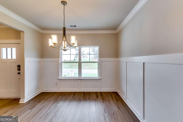 497 Principal Meridian Dr, Dallas, GA 30132 - unfurnished dining area with a decorative wall, a chandelier, wood finished floors, a wainscoted wall, and crown molding