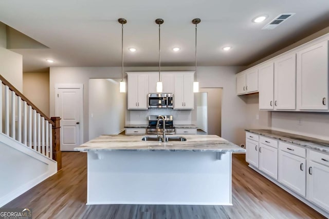 497 Principal Meridian Dr, Dallas, GA 30132 - kitchen with stainless steel appliances, a sink, wood finished floors, white cabinetry, and recessed lighting