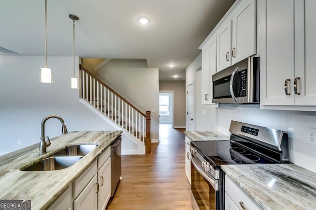 497 Principal Meridian Dr, Dallas, GA 30132 - kitchen featuring stainless steel appliances, a sink, light wood-style flooring, hanging light fixtures, and light stone counters