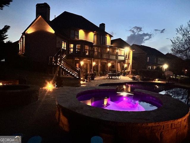 968 Woodtrace Ln, Auburn, GA 30011 - back of property featuring a chimney, stairway, a fire pit, a patio area, and a pool with connected hot tub