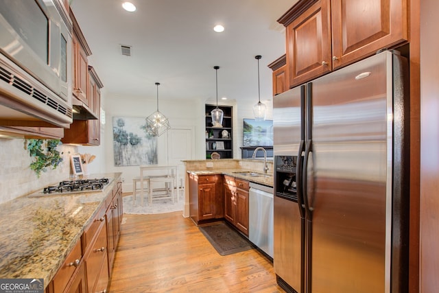 kitchen featuring visible vents, a peninsula, stainless steel appliances, a sink, and light wood-style floors