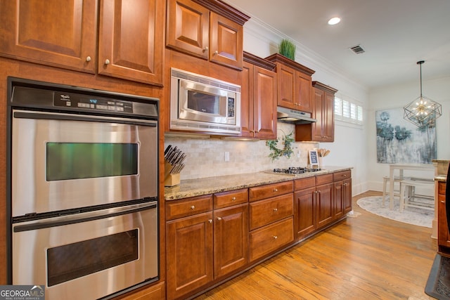 kitchen with visible vents, ornamental molding, appliances with stainless steel finishes, under cabinet range hood, and backsplash