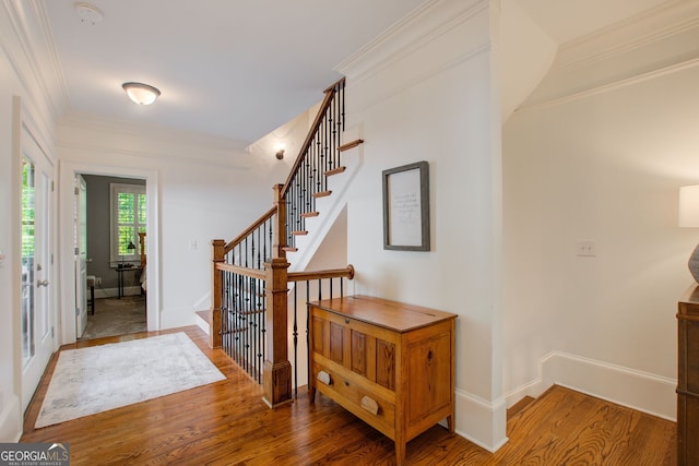 foyer featuring baseboards, stairway, wood finished floors, and ornamental molding