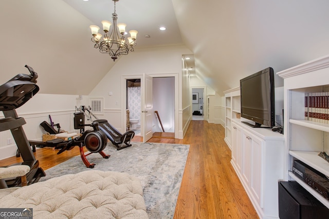 exercise area featuring vaulted ceiling, visible vents, light wood-style flooring, and an inviting chandelier