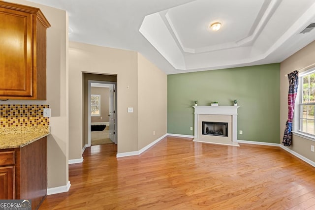 79 Tiffany Trce, Palmetto, GA 30268 - unfurnished living room featuring a raised ceiling, a fireplace with raised hearth, light wood-style floors, and baseboards