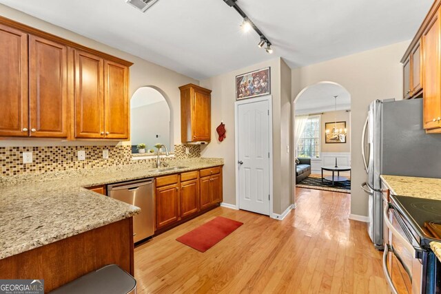 79 Tiffany Trce, Palmetto, GA 30268 - kitchen featuring brown cabinetry, arched walkways, a sink, and stainless steel appliances
