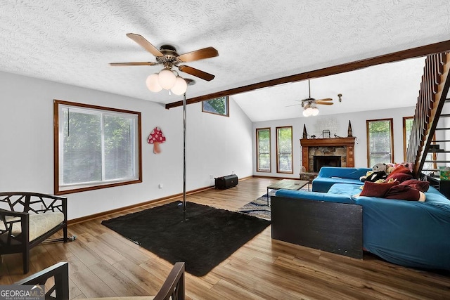living area featuring ceiling fan, wood finished floors, a textured ceiling, and vaulted ceiling with beams
