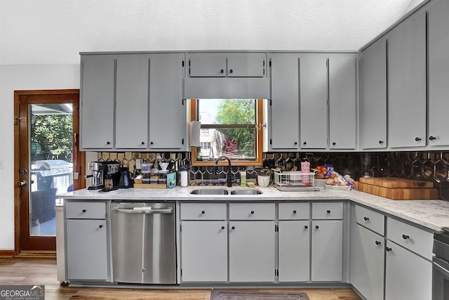 kitchen featuring a sink, a textured ceiling, dishwasher, light countertops, and gray cabinetry